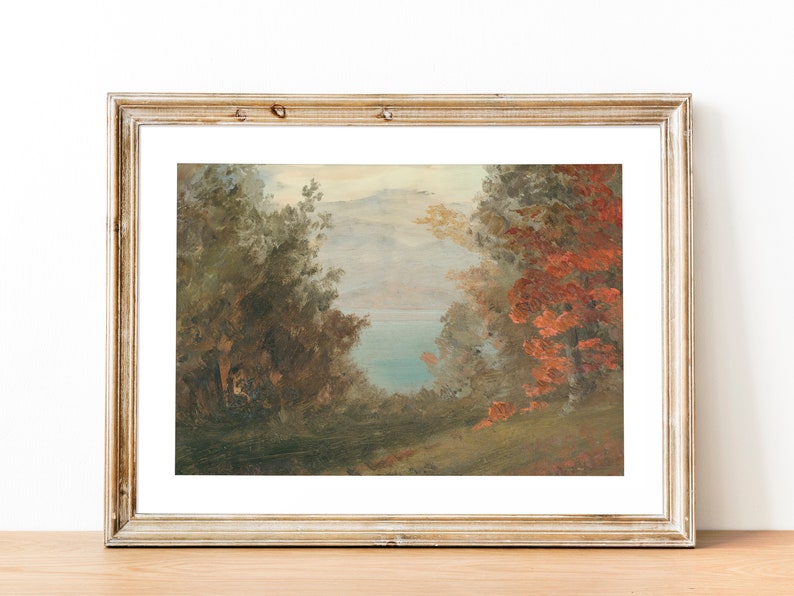 May include: A framed painting depicting a landscape scene with a lake in the distance. The foreground features trees with lush green foliage and a few trees with red leaves. The sky is a light blue with white clouds.