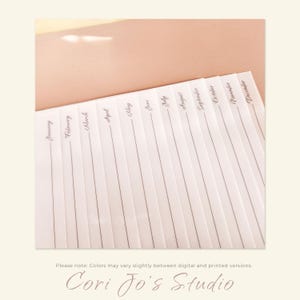 May include: A white sheet of paper with the months of the year written in cursive script. The paper is divided into sections for each month, with lines for writing.