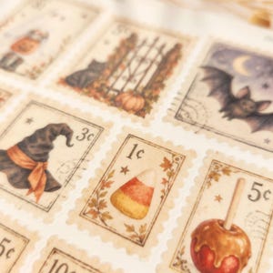 Op de afbeelding: Een vel met rechthoekige postzegelstickers met Halloween-illustraties, waaronder een zwarte kat, een vleermuis, een heksenhoed, suikerma&iuml;s en een toffee-appel. Elke postzegel heeft geschulpte randen en een numerieke waarde in centen.