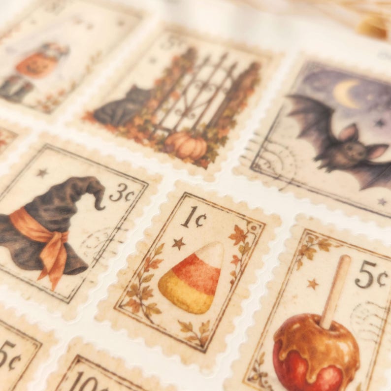 Op de afbeelding: Een vel met rechthoekige postzegelstickers met Halloween-illustraties, waaronder een zwarte kat, een vleermuis, een heksenhoed, suikerma&iuml;s en een toffee-appel. Elke postzegel heeft geschulpte randen en een numerieke waarde in centen.
