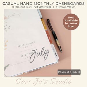 May include: A white planner with a floral design and the word "July" written in cursive. The planner has tabs for each month, and a pen is lying on top of it. The text "IF IT COMES, LET IT" and "IF IT GOES, LET IT" is printed on the planner.