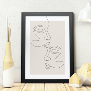 May include: A black framed print with a beige background featuring a line drawing of two faces in profile, one above the other, with their noses touching.
