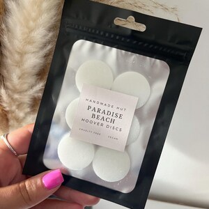 Peut inclure: Un sac refermable noir avec une &eacute;tiquette blanche qui indique "Handmade Hut Paradise Beach Hoover Discs Cruelty Free Vegan". Le sac contient six disques parfum&eacute;s ronds blancs.