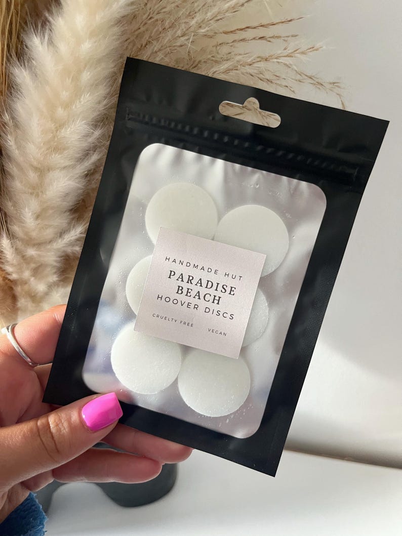 Peut inclure: Un sac refermable noir avec une &eacute;tiquette blanche qui indique "Handmade Hut Paradise Beach Hoover Discs Cruelty Free Vegan". Le sac contient six disques parfum&eacute;s ronds blancs.