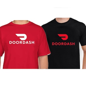 Pode incluir: Uma t-shirt vermelha de manga curta com o logótipo e texto DoorDash em branco, ao lado de uma t-shirt preta de manga curta com o logótipo e texto DoorDash em vermelho. Ambas as t-shirts têm gola redonda e um corte padrão.
