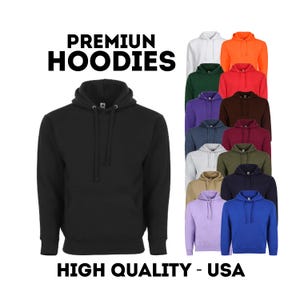 May include: A black hoodie with a front pocket and drawstring hood. The image displays a variety of colored hoodies, including white, orange, green, red, purple, brown, gray, olive, navy, tan, lavender, and blue. Text reads "PREMIUM HOODIES" and "HIGH QUALITY - USA."