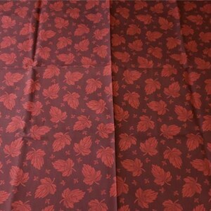 May include: Red and brown fabric with a repeating pattern of red maple leaves.