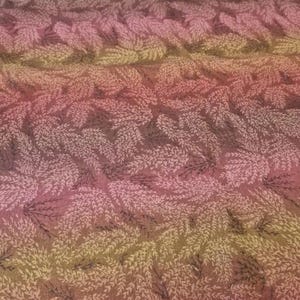 May include: A fabric featuring a repeating pattern of small, delicate fern-like leaves in shades of light pink and cream, set against a gradient background that transitions from a deep reddish-brown to a muted olive green across the surface.