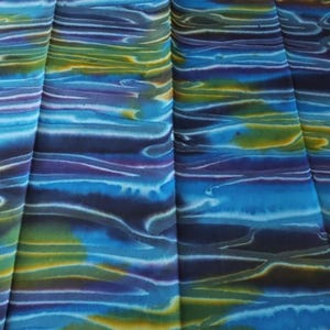 May include: Blue, green, and purple fabric with a wavy, abstract pattern. The fabric is folded in thirds.