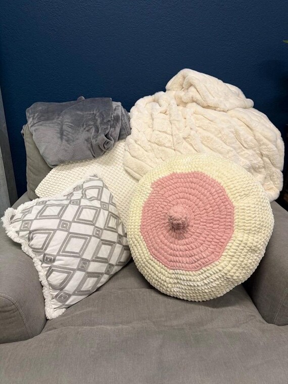 A hand-crocheted boobie throw pillow that somehow walks the line between cheeky gag gift and genuinely charming handmade decor.