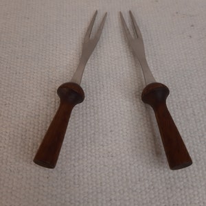 May include: Two silver forks with wooden handles. The forks have three prongs each and the handles are a dark brown colour.