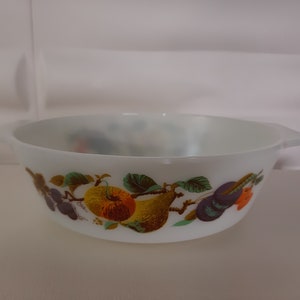 Könnte beinhalten: Weiße Keramikschüssel mit einem Fruchtdesign. Die Schüssel zeigt eine Birne, einen Apfel, Trauben und Pflaumen in Grün-, Gelb-, Orange-, Lila- und Brauntönen.