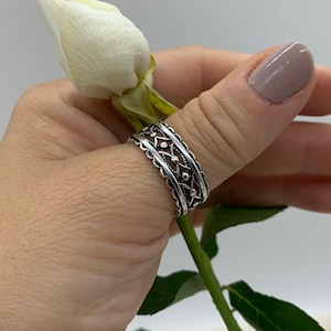 Pu&ograve; includere: Un anello per il pollice in argento con un design dettagliato e intricato. L'anello ha una fascia testurizzata e decorata con piccoli accenti rotondi.