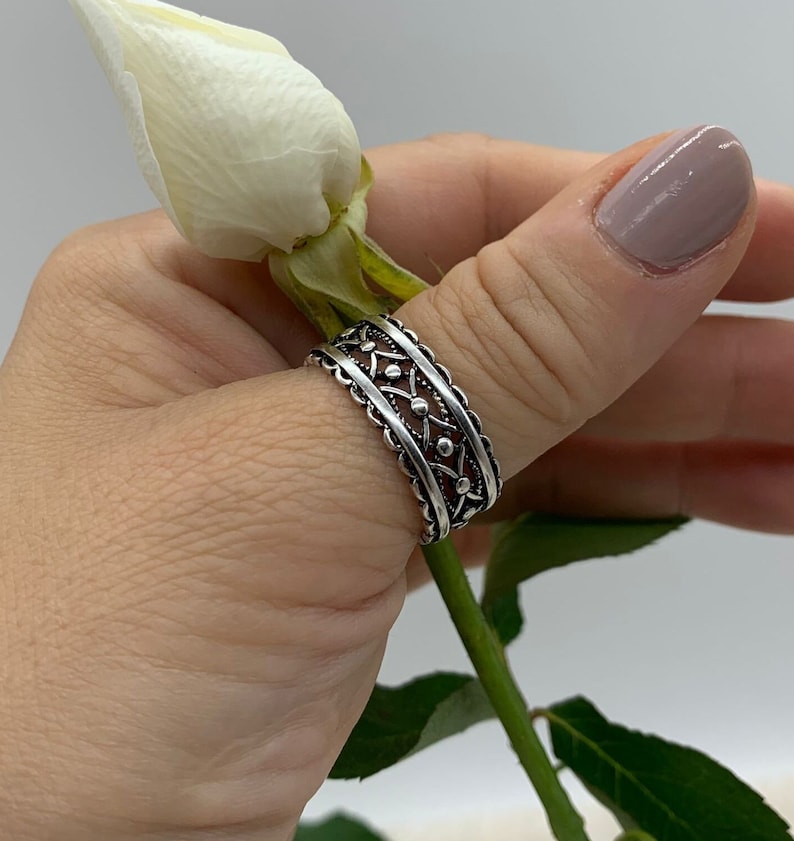 Pu&ograve; includere: Un anello per il pollice in argento con un design dettagliato e intricato. L'anello ha una fascia testurizzata e decorata con piccoli accenti rotondi.