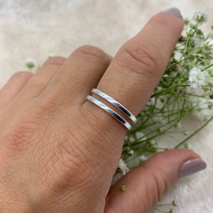 Puede incluir: Un anillo de plata con dos bandas, usado en un dedo.