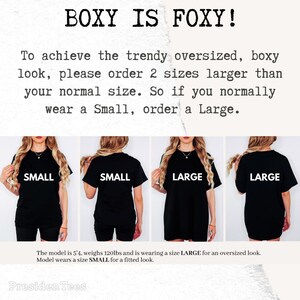 May include: Image showing four women wearing black t-shirts. The text "BOXY IS FOXY!" is at the top. The text below advises ordering two sizes larger for an oversized fit. The model is 163cm tall and weighs 54kg.