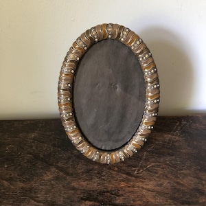 May include: An oval picture frame featuring a wavy, multi-toned brown enamel border. The frame is accented with small, clear, sparkling rhinestones embedded in a repeating pattern along the inner and outer edges of the textured, rippled frame.