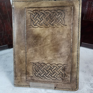 May include: A brown leather journal with a Celtic knot design embossed on the front and back covers.