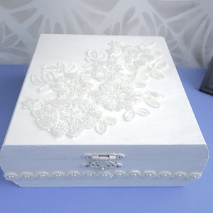 Stunning white box with spray of silk, pearl and sequined flowers on top.
