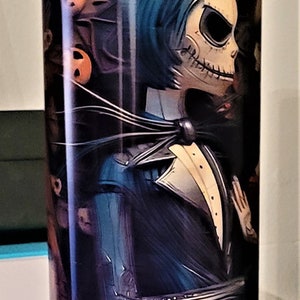 Pu&ograve; includere: Un bicchiere in acciaio inossidabile con un'immagine in bianco e nero di Jack Skellington del film Nightmare Before Christmas. L'immagine mostra Jack in completo con papillon e camicia bianca. Lo sfondo &egrave; di colore viola scuro e arancione con un motivo floreale.