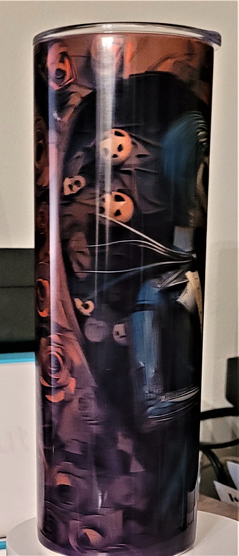 Pu&ograve; includere: Un bicchiere alto e trasparente con un design nero e arancione che presenta pi&ugrave; volti. Il design ricorda un film horror.