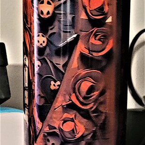 Pu&ograve; includere: Un bicchiere in acciaio inossidabile con un design nero e rosso con rose. Le rose sono stilizzate e hanno uno sfondo scuro.