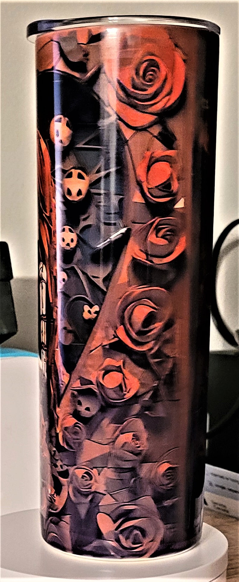 Pu&ograve; includere: Un bicchiere in acciaio inossidabile con un design nero e rosso con rose. Le rose sono stilizzate e hanno uno sfondo scuro.