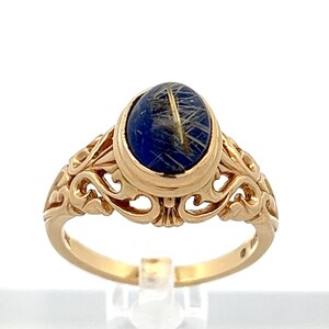 May include: A gold ring with an oval blue stone set in a filigree design.