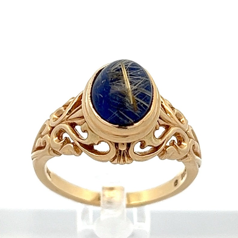 May include: A gold ring with an oval blue stone set in a filigree design.