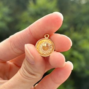 May include: A gold-colored charm in the shape of a sombrero. The charm has a detailed design and is perfect for adding a touch of Mexican flair to jewelry.
