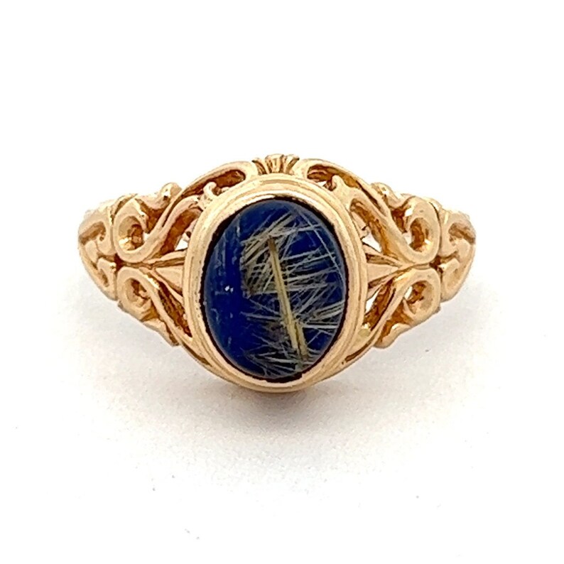 May include: A gold ring with an oval-shaped blue stone set in a filigree design.