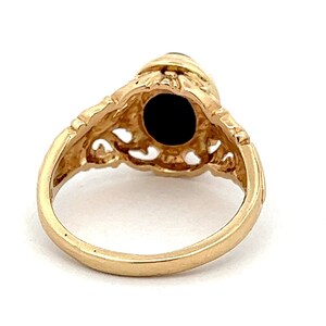 May include: A gold ring with a black stone set in a filigree design.