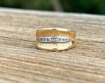 Könnte beinhalten: Ein goldener Ring mit einer strukturierten Band und einer Reihe kleiner Diamanten, die in Weißgold gefasst sind.