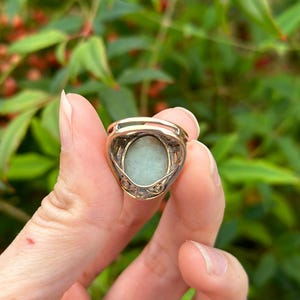 May include: A gold ring with a green oval gemstone set in a delicate filigree design.
