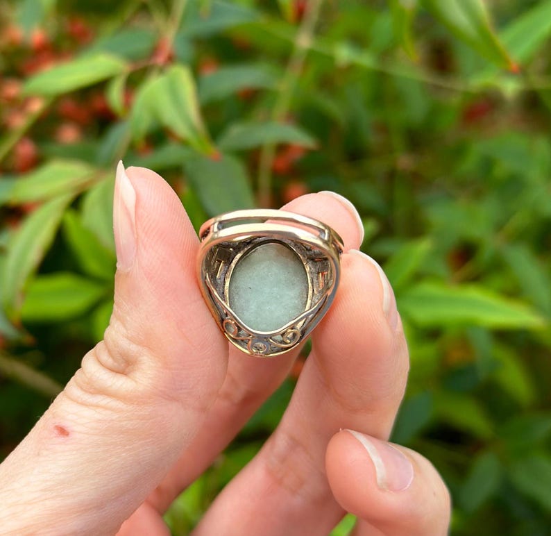 May include: A gold ring with a green oval gemstone set in a delicate filigree design.