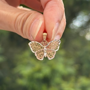 May include: A delicate gold butterfly pendant with intricate filigree details. The pendant is made of two-toned gold, with a yellow gold body and white gold accents.