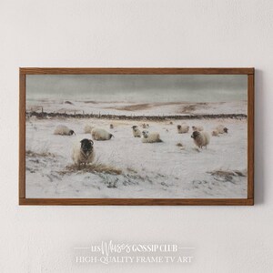 Peut inclure: Une impression encadrée représente un paysage enneigé avec un troupeau de moutons. Les moutons, dont certains ont le visage noir, sont dispersés dans un champ enneigé. L'œuvre est encadrée dans un cadre en bois marron. Le texte en bas indique "HIGH-QUALITY FRAME TV ART".