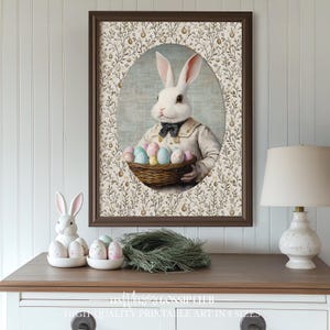 Peut inclure: Une impression encadrée d'un lapin blanc tenant un panier d'œufs de Pâques colorés. Le lapin porte un nœud papillon et une chemise blanche. L'arrière-plan est un motif floral.