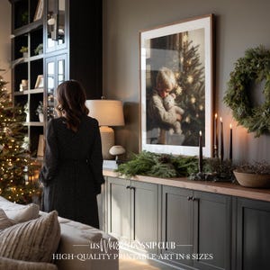Peut inclure: Une impression encadrée d'un enfant étreignant un ours en peluche devant un sapin de Noël. L'impression est affichée au-dessus d'un meuble sombre avec un dessus en bois, décoré de verdure et de bougies. Une femme en robe noire se tient à proximité. Le texte indique "HIGH-QUALITY PRINTABLE ART IN 8 SIZES."