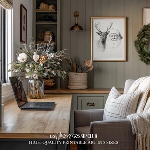 Peut inclure: Un bureau à domicile avec un bureau en bois, un ordinateur portable et une impression encadrée du Père Noël et d'un renne. Un vase de fleurs et un panier tressé avec des plantes séchées sont sur le bureau. Le texte "HIGH-QUALITY PRINTABLE ART IN 8 SIZES" est en bas.