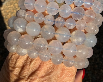 May include: A stack of clear quartz crystal bracelets with a frosted finish. The bracelets are made of round beads and are stacked on top of each other.