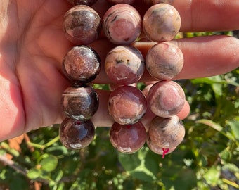 May include: A bracelet made of pink and brown striped round beads. The beads are about 1 inch in diameter.