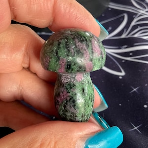 Puede incluir: Un hongo de piedra preciosa tallado de color verde y rosa. El hongo está pulido y tiene una superficie lisa.