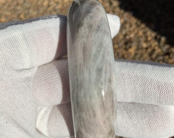 May include: A smooth, polished, gray and white banded stone bangle bracelet. The stone has a swirling pattern.
