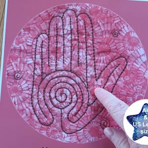 May include: A pink and white fabric circle with a black outline of a hand with a spiral in the center. The fabric has a tie-dye pattern. The circle is on a pink background. A4 & US Letter size.