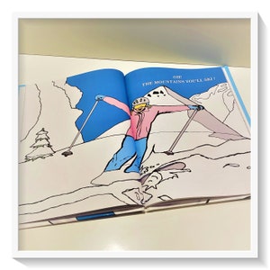 Może przedstawiać: Otwarta książka z ilustracją osoby zjeżdżającej na nartach z g&oacute;ry. Tekst na stronie brzmi "Oh! The mountains you'll ski!"