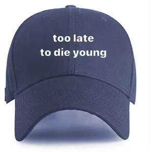 May include: A navy blue baseball cap with white embroidered text that reads "too late to die young".