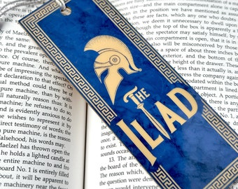 May include: A blue bookmark with a gold Greek key border and a gold illustration of a helmet. The bookmark has the text "The Iliad" in gold letters.