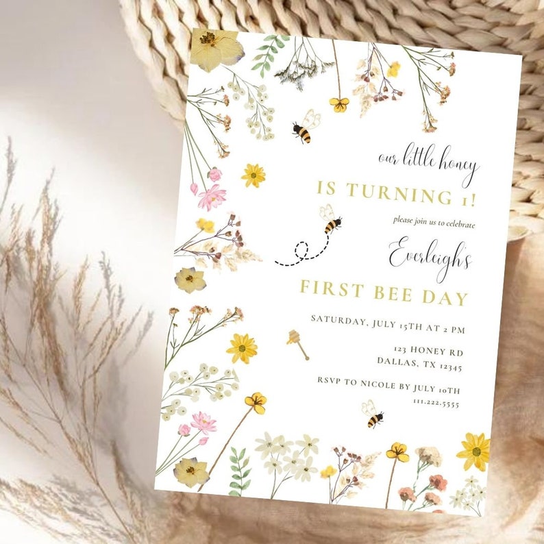 Puede incluir: Una invitaci&oacute;n blanca con un dise&ntilde;o floral con flores amarillas, rosas y blancas. El texto dice "our little honey is turning 1!" y "Everleigh's First Bee Day". La invitaci&oacute;n incluye detalles del evento, como la fecha, la hora, la direcci&oacute;n y la informaci&oacute;n de RSVP.