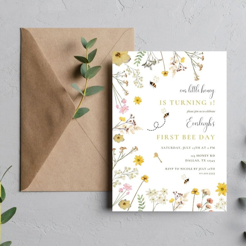Puede incluir: Una invitaci&oacute;n blanca con un borde floral y un dise&ntilde;o de abeja. El texto dice "our little honey is turning 1!" y "First Bee Day". La invitaci&oacute;n es para una fiesta de primer cumplea&ntilde;os e incluye la fecha, la hora, la direcci&oacute;n y la informaci&oacute;n de RSVP.
